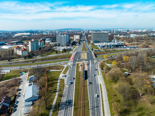 Fototapeta premium City highway multilevel crossroad in Krakow, Poland. Tramway and tram near a tram stop, cars, zebra crossings, cycle tracks and public park. Aerial view