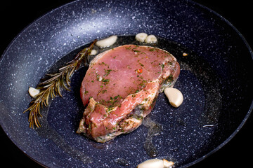Grilled premium rib eye beef steak in the pan, cooking steak in the kitchen on a dark background. Overhead shot of chef preparing ribeye with butter, thyme and garlic.