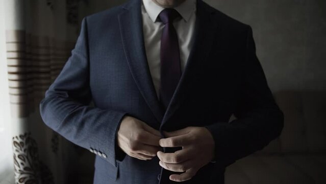 Male businessman buttoning his jacket near the window getting ready for a business meeting
