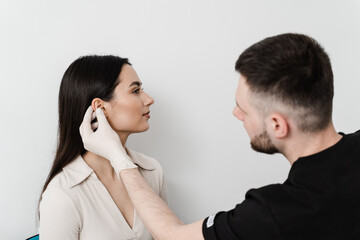 Otoplasty ear surgery. Surgeon doctor examines girl ears before otoplasty cosmetic surgery. Otoplasty surgical reshaping of pinna and ear.