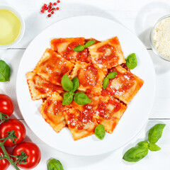 Ravioli pasta meal from Italy for lunch dish with tomato sauce top view on a plate and wooden board square