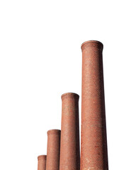 Old brick industrial smokestacks isolated with cut out sky.