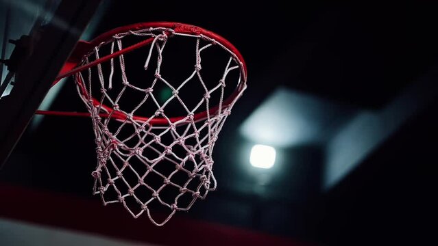 A basketball hits the basket in an indoor sports arena.