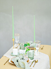 An elegant table arrangement for two. Sophisticated green candles and the combination of white and gold create a luxury setting for a special occasion, as a romantic date or an anniversary dinner.