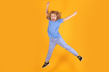 Fototapeta na wymiar Full length of excited kid jumping. Boy jumping. Full size of kid boy have fun jump up isolated over yellow background.