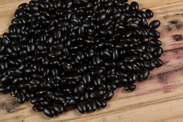 heap of black beans scattered over rustic wood