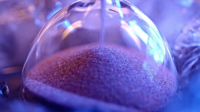 Hourglass on blue background with falling sand