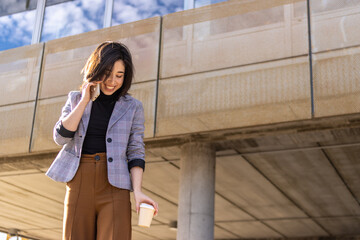 Smiling latin businesswoman takes a call on his mobile phone out of his office building, demonstrating his professionalism and dedication to his work.