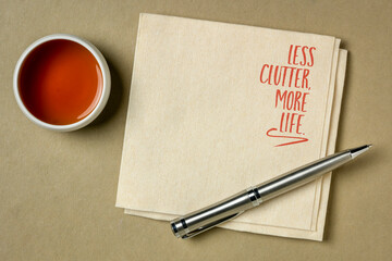less clutter, more life - decluttering, minimalism and simplicity concept, handwriting on a napkin with a copy space