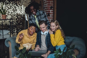 Diverse group of college students, friends, young people watching movies or cinema together on laptop, have fun, eating popcorn. Concept of international friendship, leisure time, home activity
