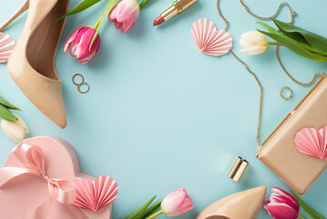 Chic and stylish top view flat lay concept featuring high heels, a trendy handbag, a gift box, tulip flowers, lipstick on a pastel blue background with copyspace