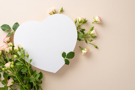 Top view flat lay image of small, delicate roses on a calming pastel beige background with an empty heart for an advertisement or message