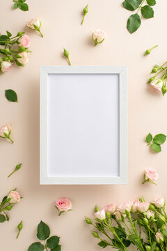 Simple beauty of small roses on a calming pastel beige background makes top vertical view flat lay an ideal backdrop for advertising or branding, with a blank frame