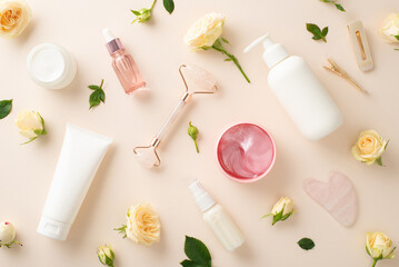 Trendy skin care concept. A top view of pump bottles, serum, and massage face rollers surrounded by beautiful roses on a pastel beige background