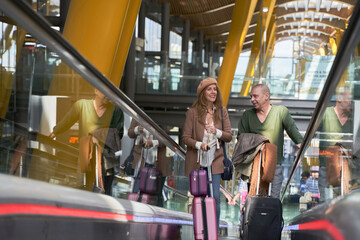 middle-aged couple carrying suitcases up the escalator at the airport station