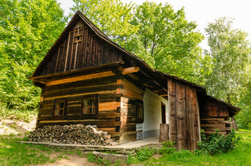 Fototapeta premium Beautiful wooden old house in green forest with pile of wood stored in front, ready for winter.