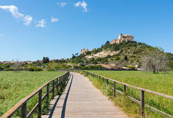 Fototapeta na wymiar Artá Castle and Sant Salvador Sanctuary, in the village of Artá, in Mallorca (Balearic Islands, Spain). View from the wooden path at the foot of the hill, with the green countryside in spring.