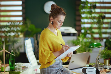 trendy business owner woman in sweater in green office