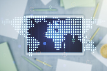 Abstract creative world map and modern digital tablet on background, top view, international trading concept. Multiexposure
