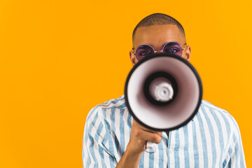 Front view of African American man speaking into a megaphone on orange background. High quality...