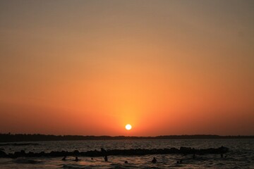 La cálida puesta de sol tiñe el cielo y el mar, creando una vista impresionante en la playa.