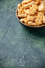 front view little salted crackers inside plate on dark background crisp color snack cips salt pepper