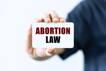 Abortion law text on blank business card being held by a woman's hand with blurred background. Business concept about abortion law.