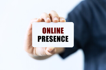 Online presence text on blank business card being held by a woman's hand with blurred background. Business concept about online presence.