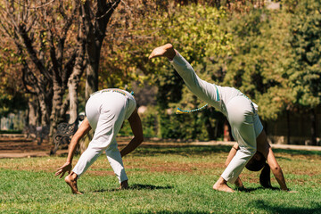 mujeres practicando patadas, ejercicios y capoeira en la ciudad con su ropa de capoeira en un...