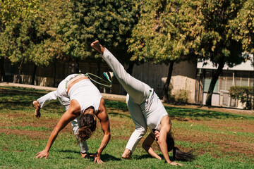 mujeres practicando patadas, ejercicios y capoeira en la ciudad con ropa de capoeira en un parque...
