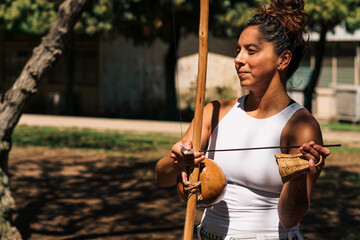 mujer morena tocando berimbau instrumento de percusión de capoeira, en un parque con un día...