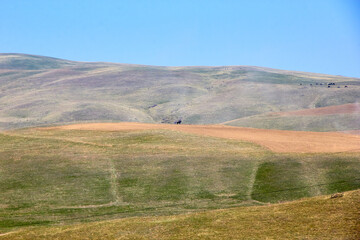 Obraz premium A shepherd on a horse herds a herd of horses far away in the mountains