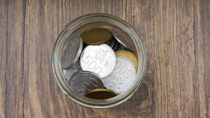 Indonesia silver gold rupiah coins in glass jar. Selective focus