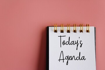 Notebook with text TODAY'S AGENDA on pink background with copy space