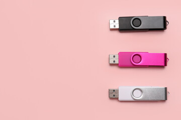 Set of USB flash drives on pink background