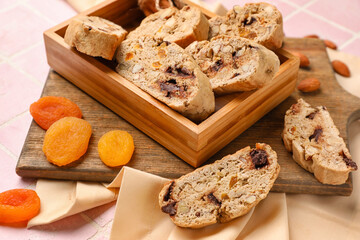 Wooden box with tasty biscotti cookies and dried apricots on table, closeup