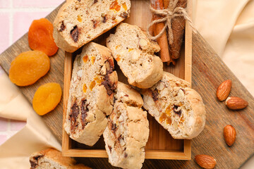 Wooden box with tasty biscotti cookies, almonds and dried apricots on table, closeup