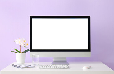 Workplace with computer, mobile phone and flower near lilac wall