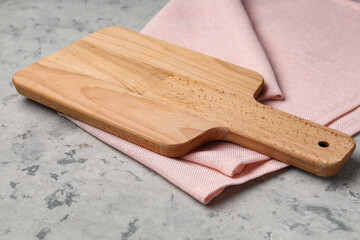 Wooden cutting board with napkin on grunge background, closeup