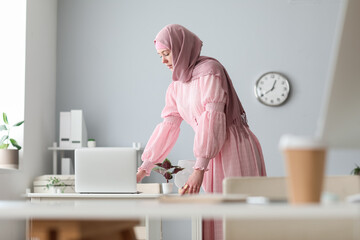 Muslim female programmer working with laptop at table in office