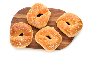 Wooden board of tasty bagels with sesame seeds on white background
