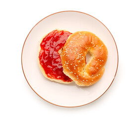 Plate of tasty bagel with strawberry jam on white background