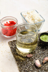 Bottle of vinegar, boiled rice, ginger and nori sheet on light background, closeup