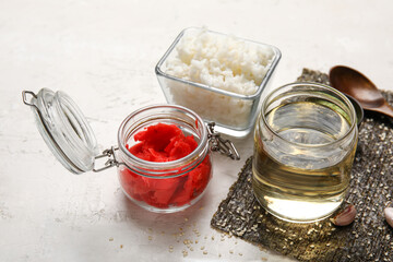 Bottle of vinegar, boiled rice, ginger and nori sheet on light background
