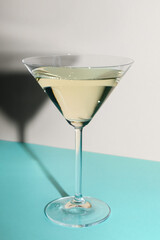 Glass of martini on color background