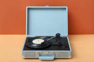 Fototapeta premium Record player with vinyl disk on table near orange wall