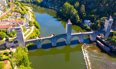 View from drone of medieval fortified arched Pont du Diable or Valentre bridge on river Lot in French town of Cahors in summer
