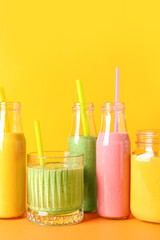 Fototapeta na wymiar Glasses and bottles of colorful smoothie on color background