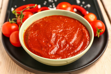 Bowl with tasty tomato paste on table, closeup