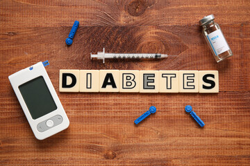 Word DIABETES with glucometer, syringe and insulin on wooden background